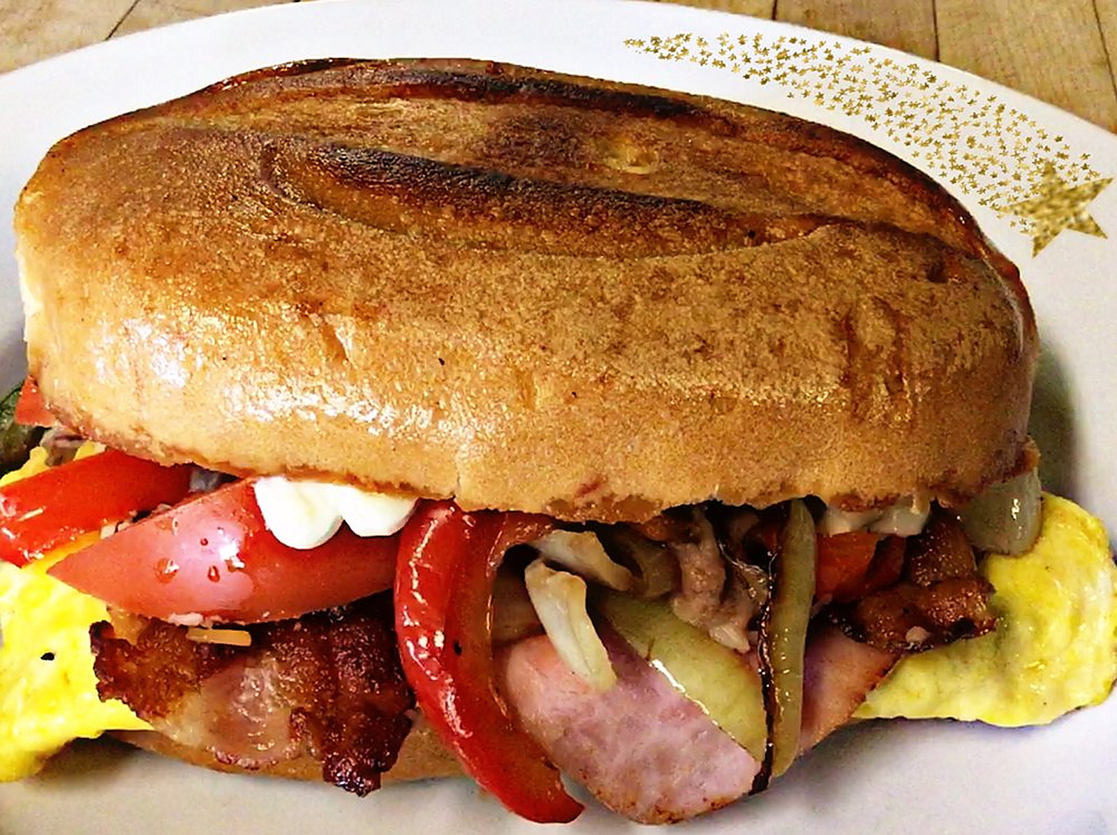 Breakfast sandwich on a toasted roll — Eggs, bacon, ham and grilled peppers